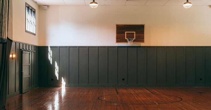 Empty indoor basketball court with hanging lights and a polished wood floor waiting to be used
