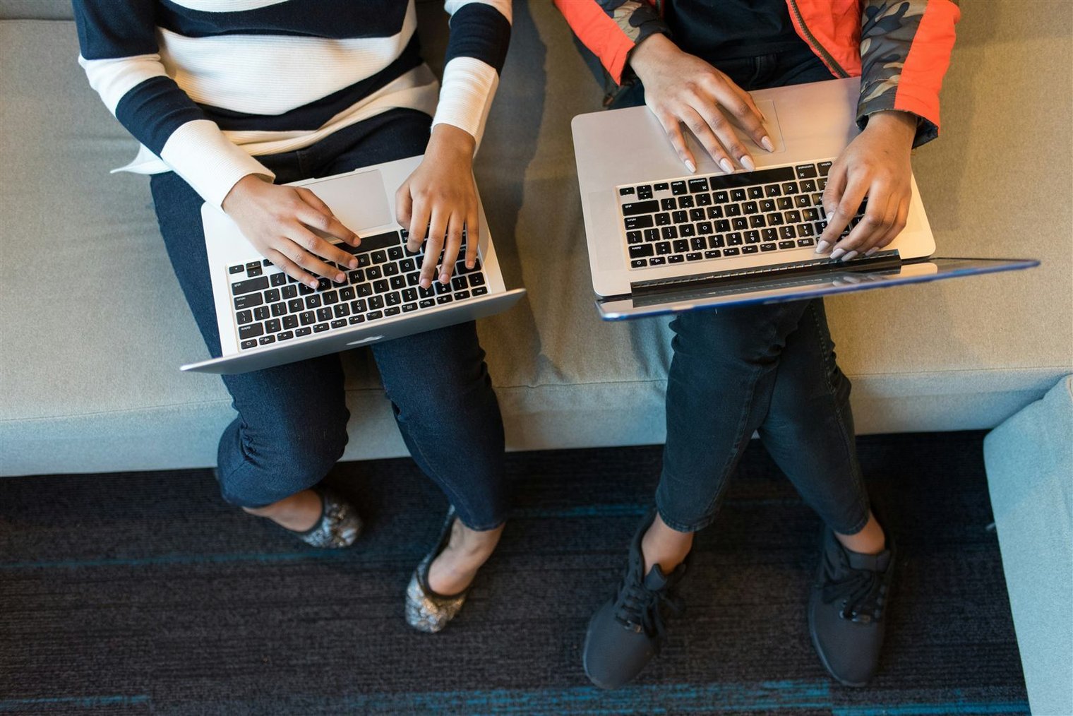 Two staff members working side by side on laptops, moving league records online