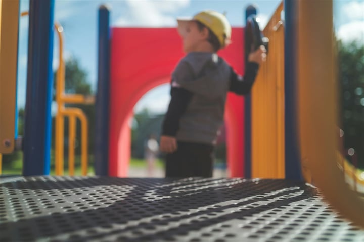 Preschool-age child playing on colorful playground equipment at a recreation facility