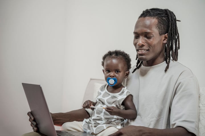 A father and his young daughter bonding while using a laptop at home.